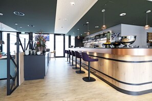Un espace bar moderne doté d’un comptoir incurvé, de tabourets de bar et d’une variété de bouteilles et de verres.