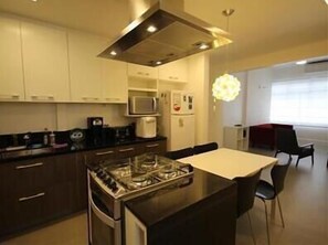 Una cucina moderna con mobili scuri, un fornello a gas, un forno a microonde e un'area pranzo con tavolo e sedie.