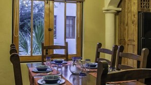 Un coin repas agrémenté d’un lustre, d’une table en bois, de chaises et d’une fenêtre donnant sur un paysage verdoyant.