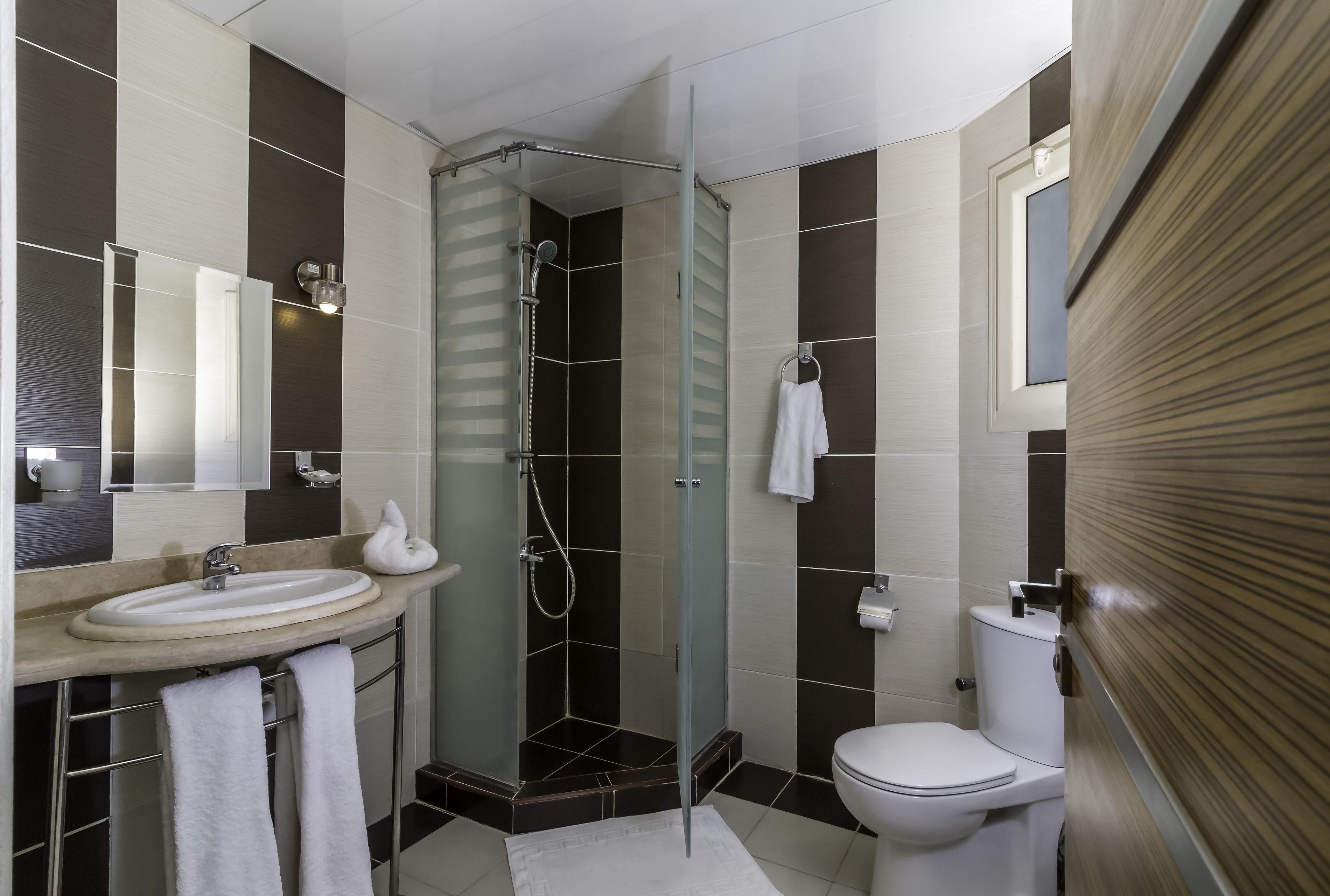 A modern bathroom with a glass shower enclosure, a sink with a mirror, and a toilet.