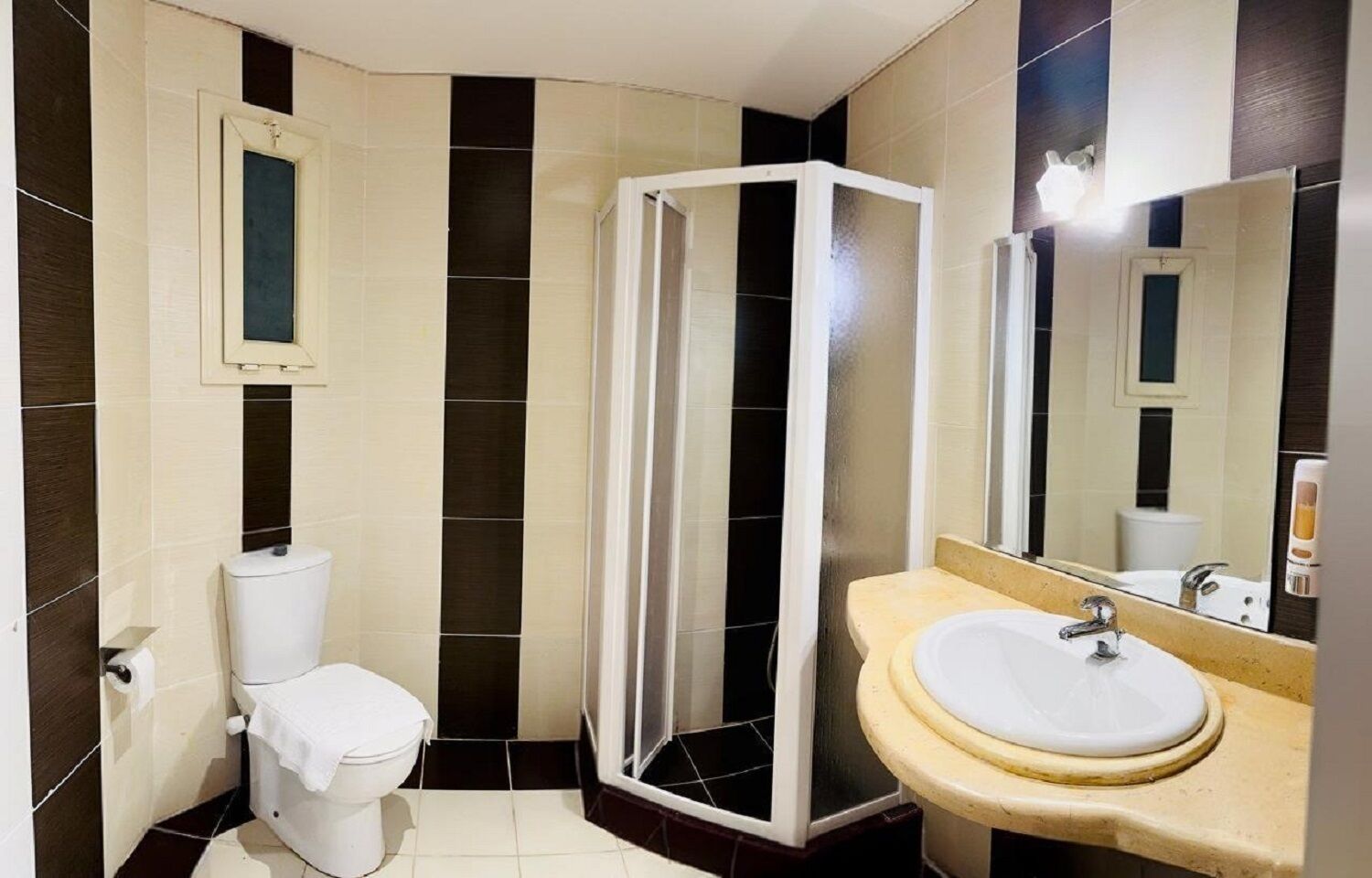 Un baño con inodoro, cabina de ducha y lavamanos con espejo.