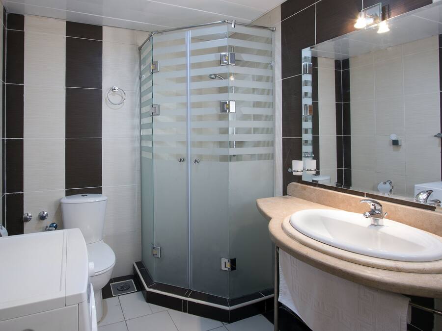 A modern bathroom with a glass shower enclosure, a white sink, and a toilet.