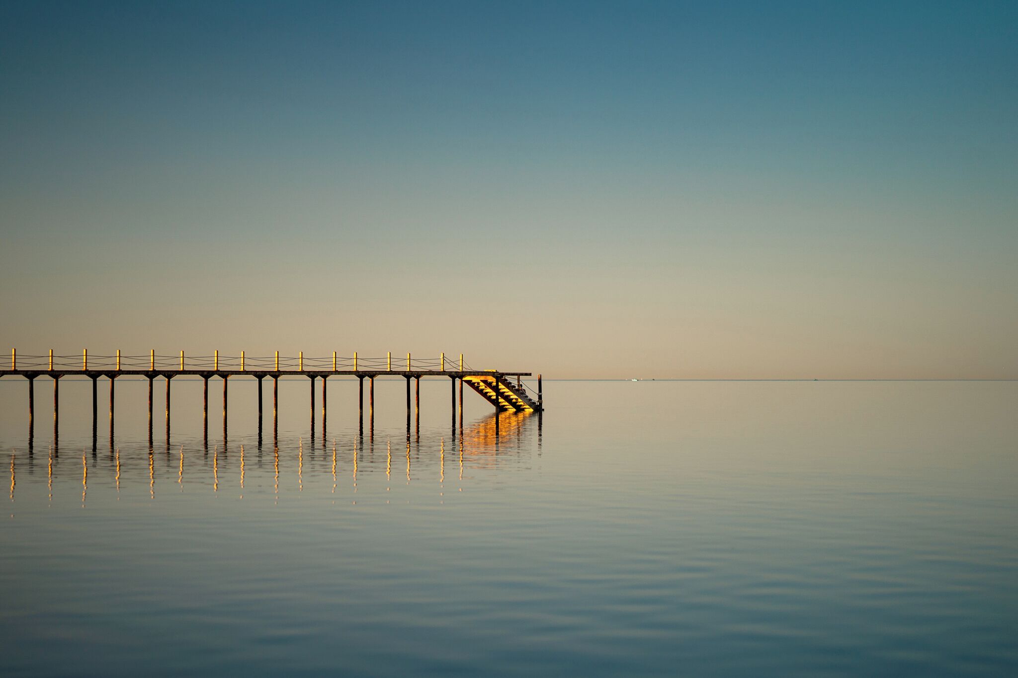 Un muelle largo que se adentra en aguas tranquilas bajo un cielo despejado.