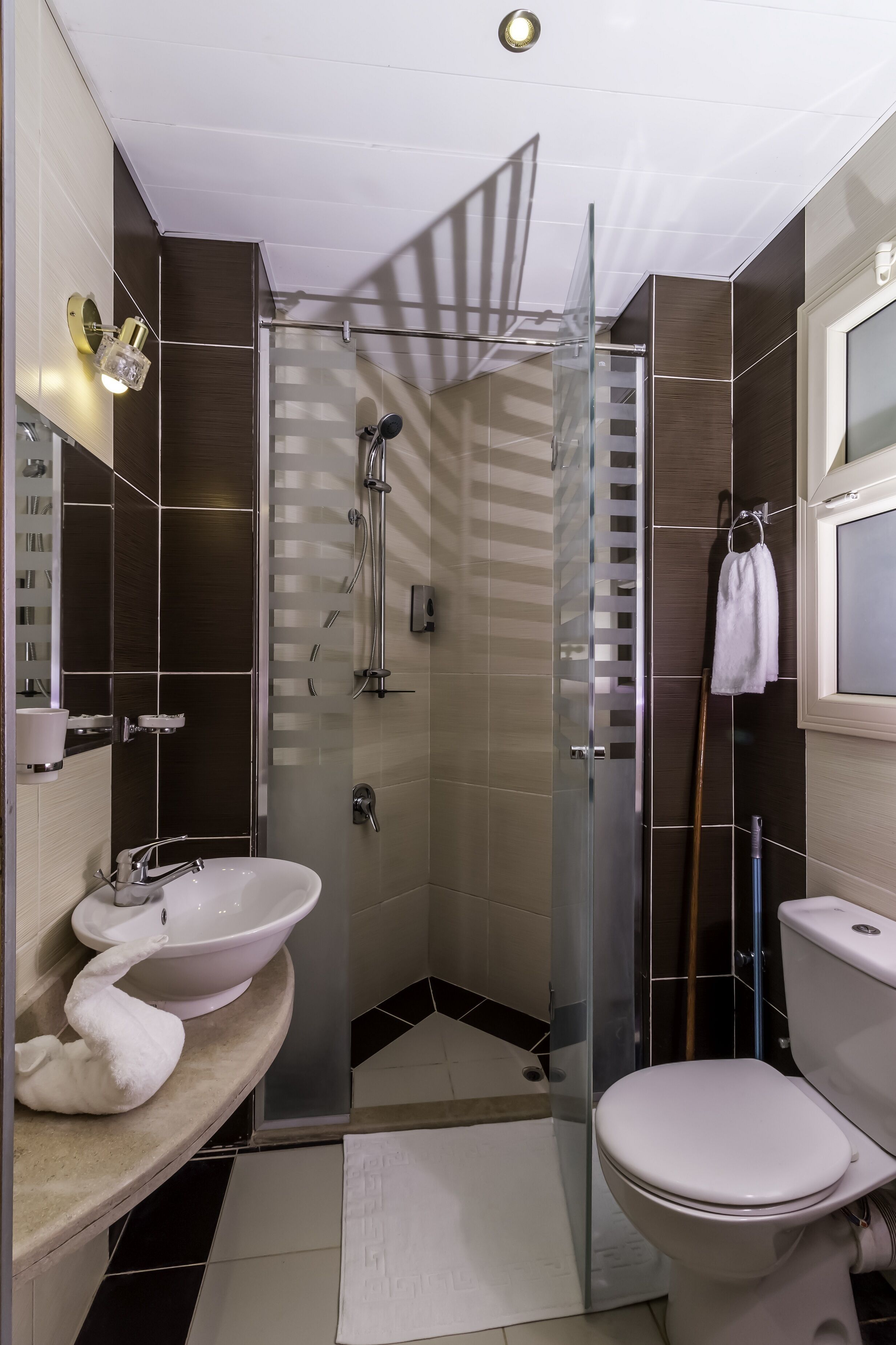 A modern bathroom with a glass-enclosed shower, a white sink, and a toilet.