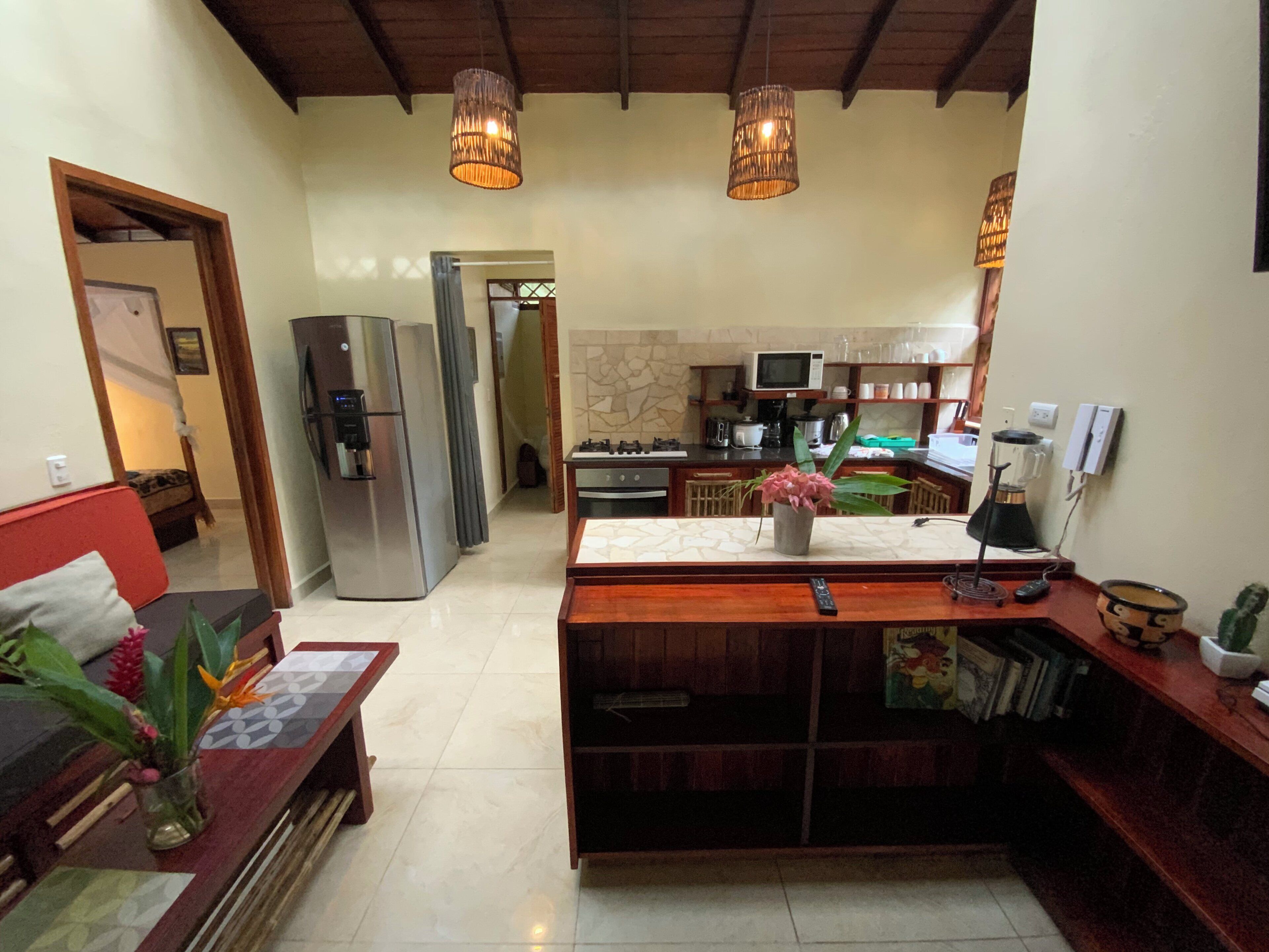A spacious living area with a wooden dining table, a sofa, and a kitchen in the background.