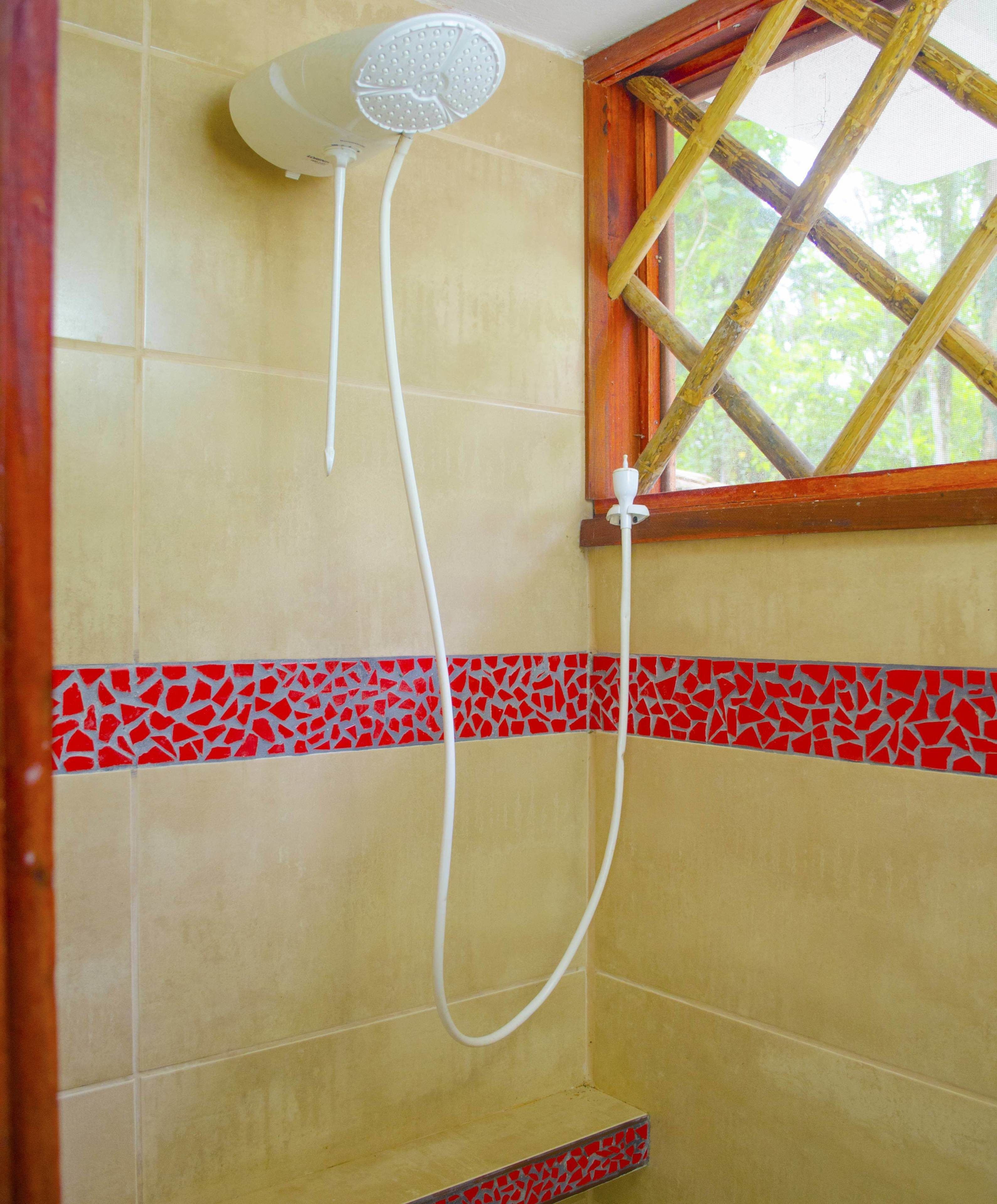A shower with a handheld showerhead and a wall-mounted control.