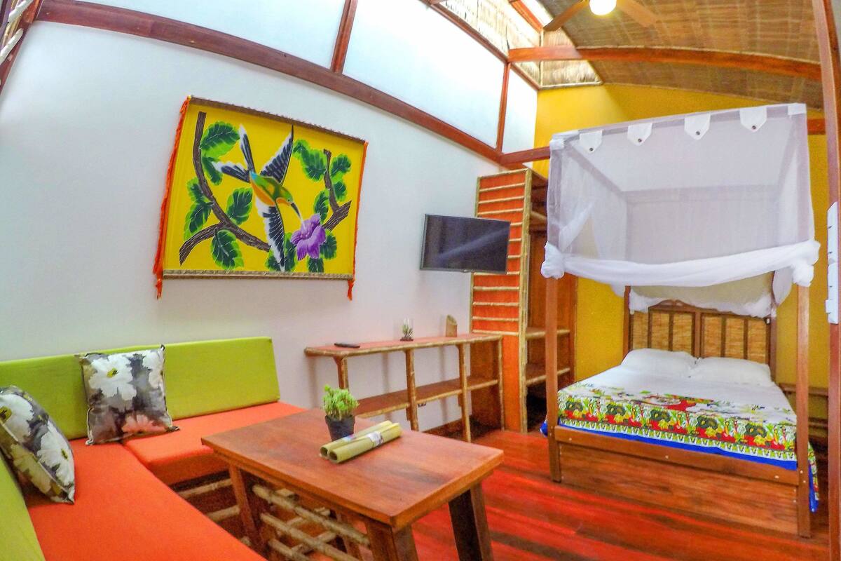 A room with a bed, a sofa, a table, and a painting on the wall.