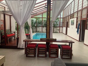 A spacious indoor area with a pool, wooden furniture, and large windows. - Uva Blue Villas (Cahuita)
