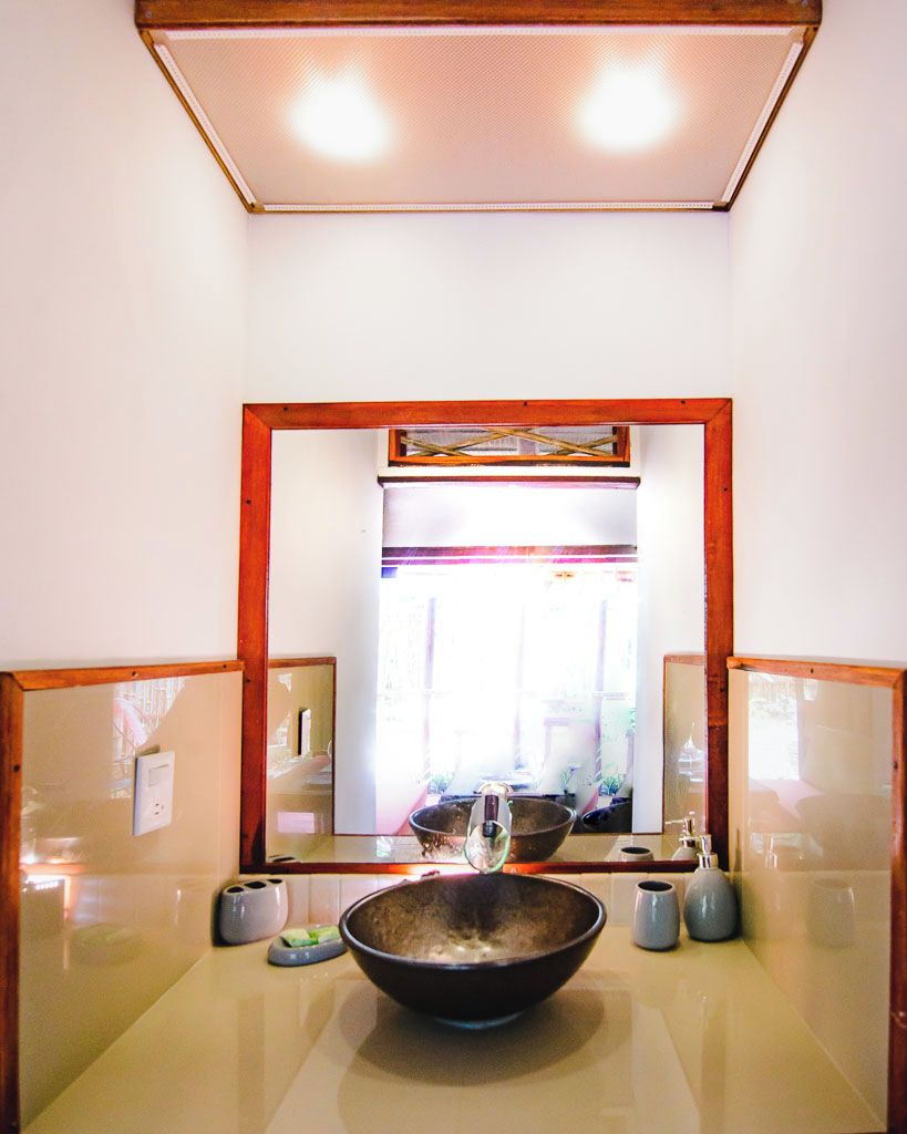 Un baño con un espejo grande, un lavabo y una ventana con cortinas.