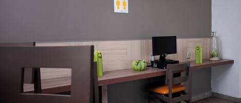 A workspace with two desks, chairs, a computer, and a small decorative vase.