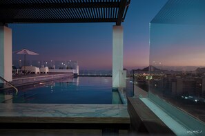 An infinity pool with a clear view of the city skyline at dusk.