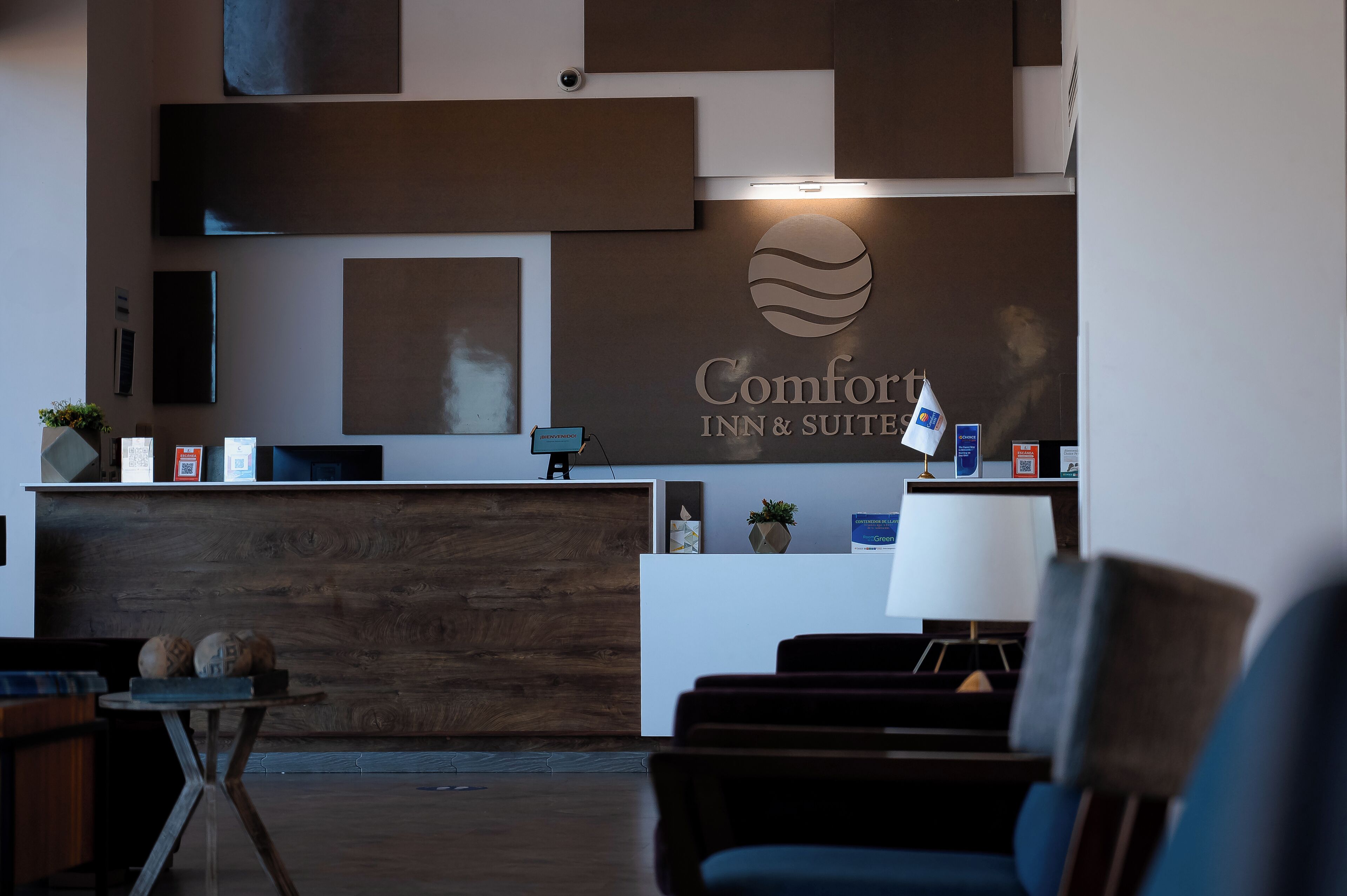 A hotel reception area with a modern design, featuring a reception desk, seating area, and a large wall-mounted sign.