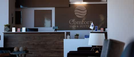 A hotel reception area with a modern design, featuring a reception desk, seating area, and a large wall-mounted sign.