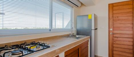 A modern kitchen with a gas stove, sink, and stainless steel refrigerator.