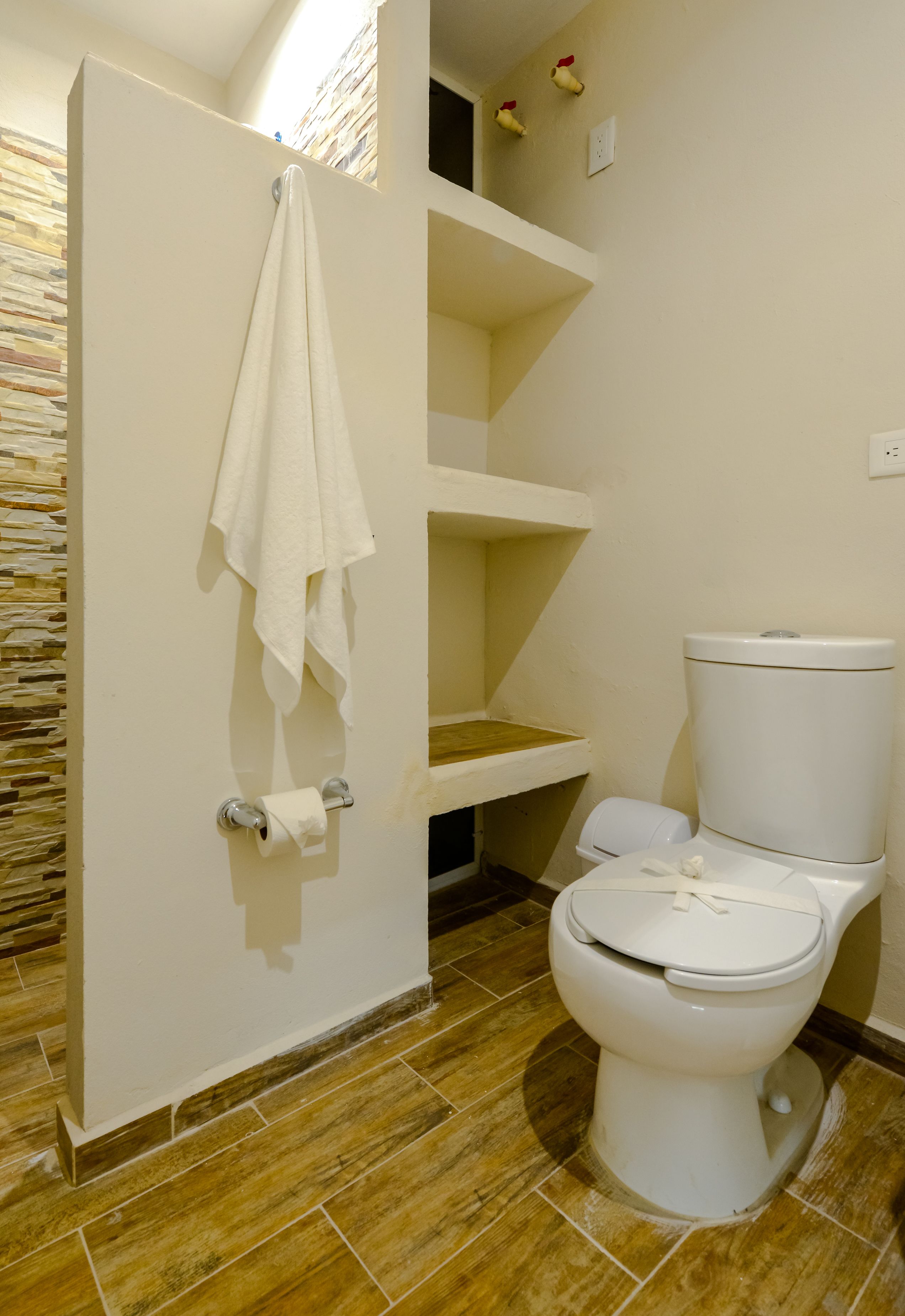 A bathroom with a toilet, a towel hanging on a rack, and a shower area.