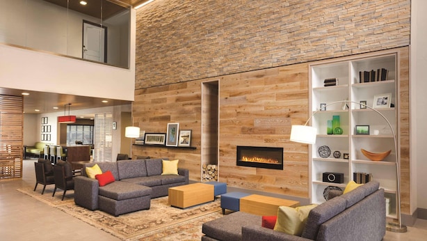 A modern living room with a fireplace, a bookshelf, and a dining area. - Country Inn & Suites by Radisson Lawrence (Lawrence)