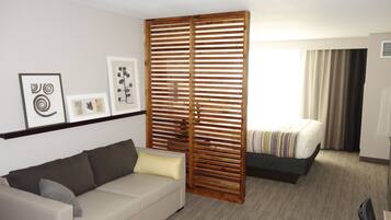 Ein Hotelzimmer mit einer Couch, einem Bett, einer Holzwand und Bildern an der Wand.