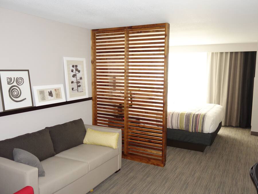 Ein Hotelzimmer mit einer Couch, einem Bett, einer Holzwand und Bildern an der Wand.