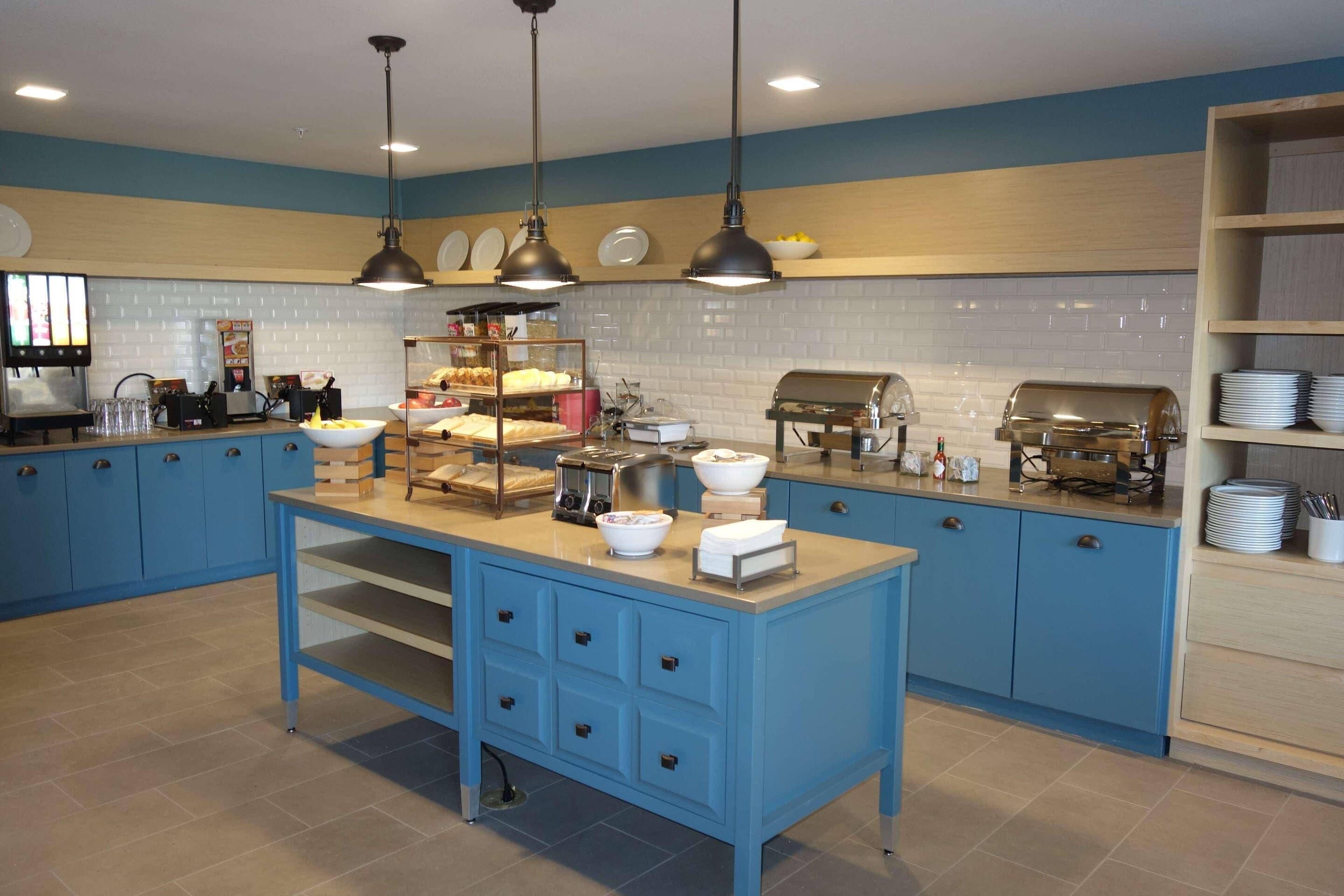 A kitchen with blue cabinets, a central island, and various appliances like a coffee machine and toaster.