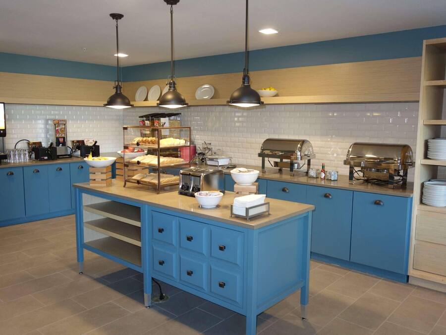 A kitchen with blue cabinets, a central island, and various appliances like a coffee machine and toaster.