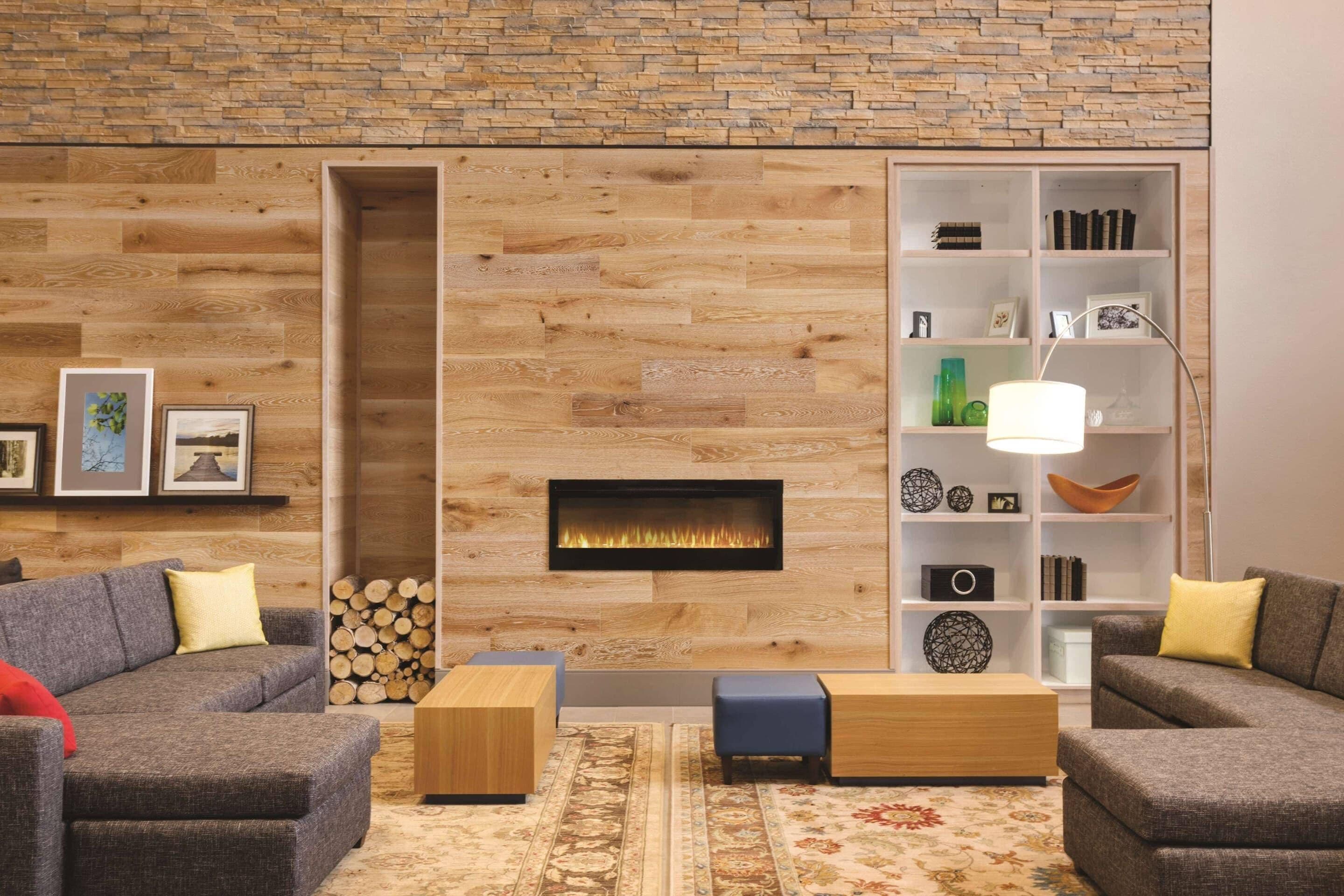 A modern living room with a fireplace, wooden wall paneling, a bookshelf, and two sofas.