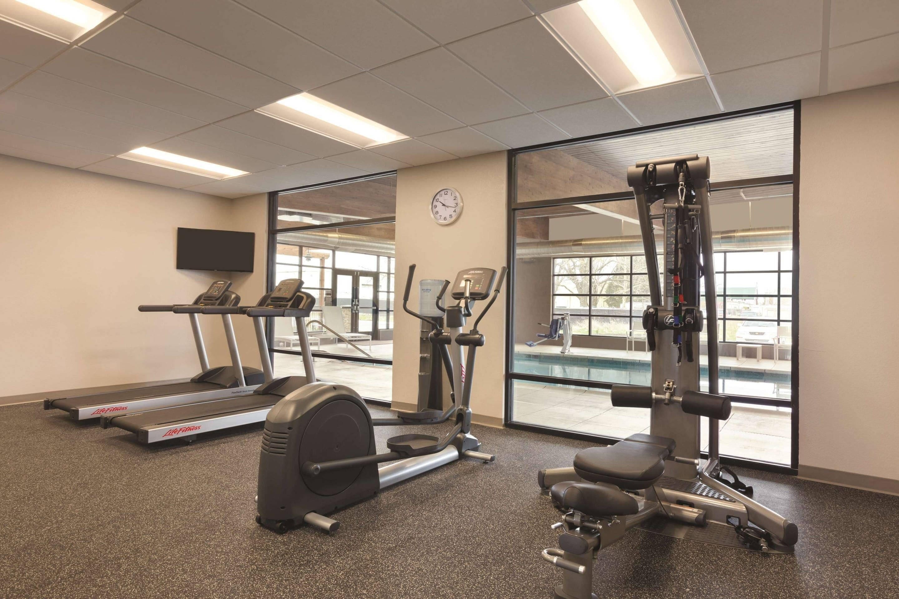 Un gimnasio con cintas de correr, elípticas y máquinas de pesas.