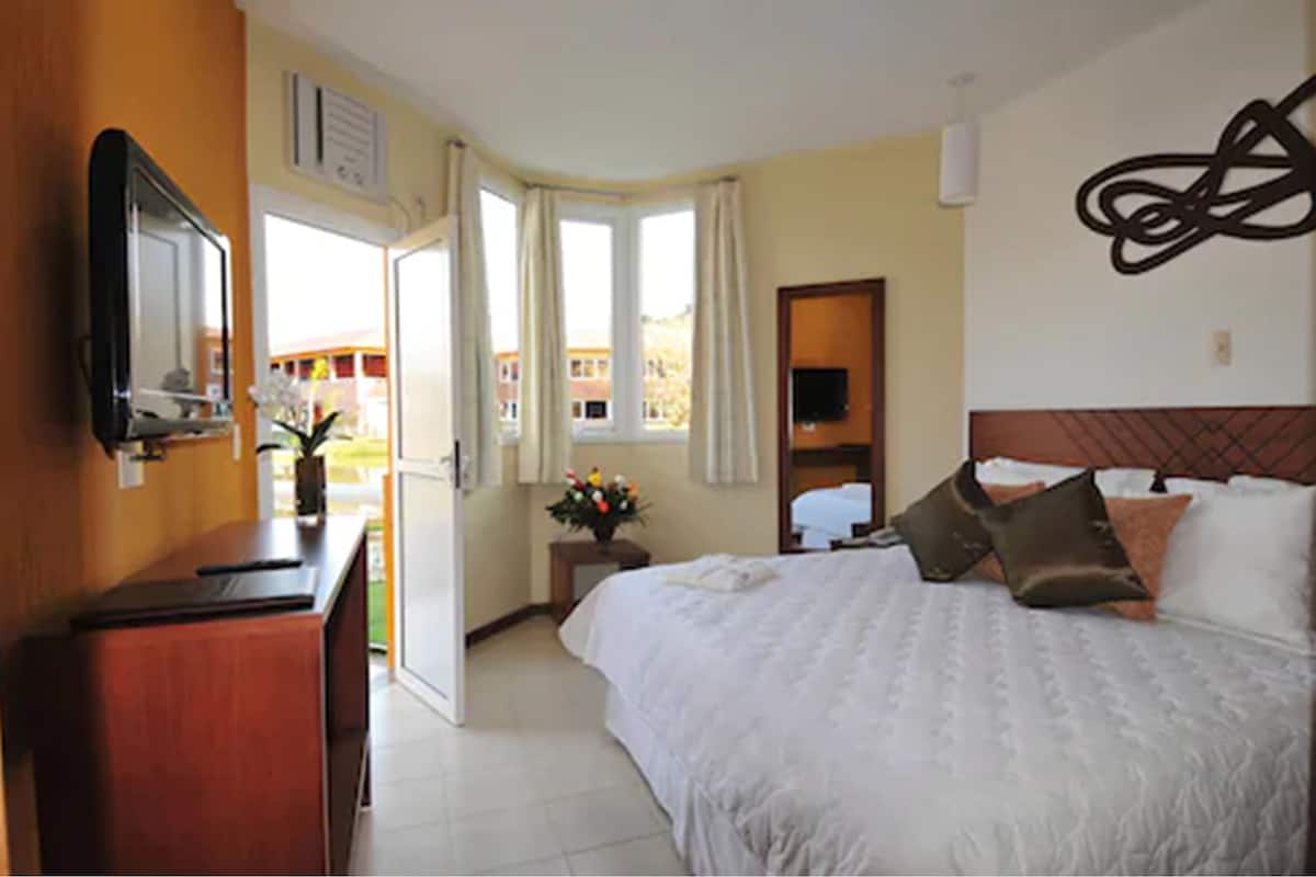 Ein Hotelzimmer mit Bett, Schreibtisch, Spiegel und einem Fenster mit Vorhängen.