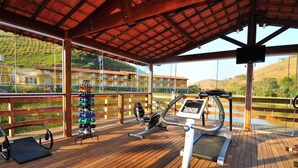 An outdoor gym area with exercise equipment, a wooden deck, and a view of a hillside. - Vassouras Eco Resort (Vassouras)