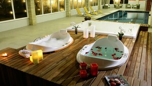 A spa area with two hot tubs, wooden flooring, and a pool. - Vassouras Eco Resort (Vassouras)