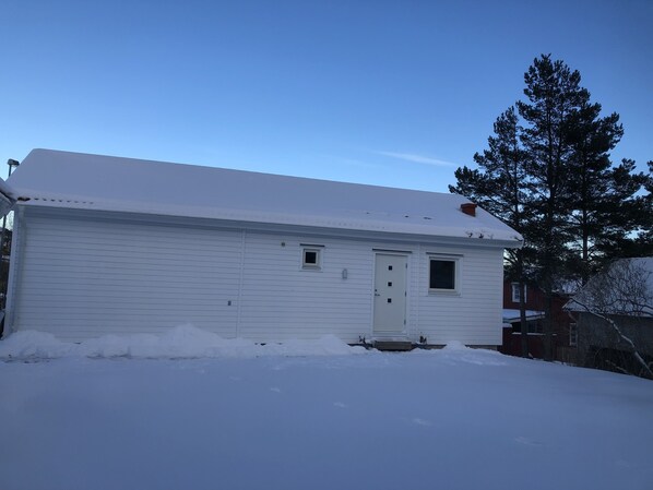 A white single-story house with a snow-covered roof and a small porch. - Great Stay Guest House Sandviken (Sandviken)