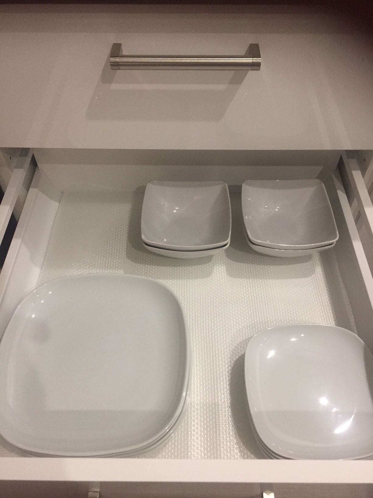 En skuffe med tre hvide tallerkener og en større hvid skål.