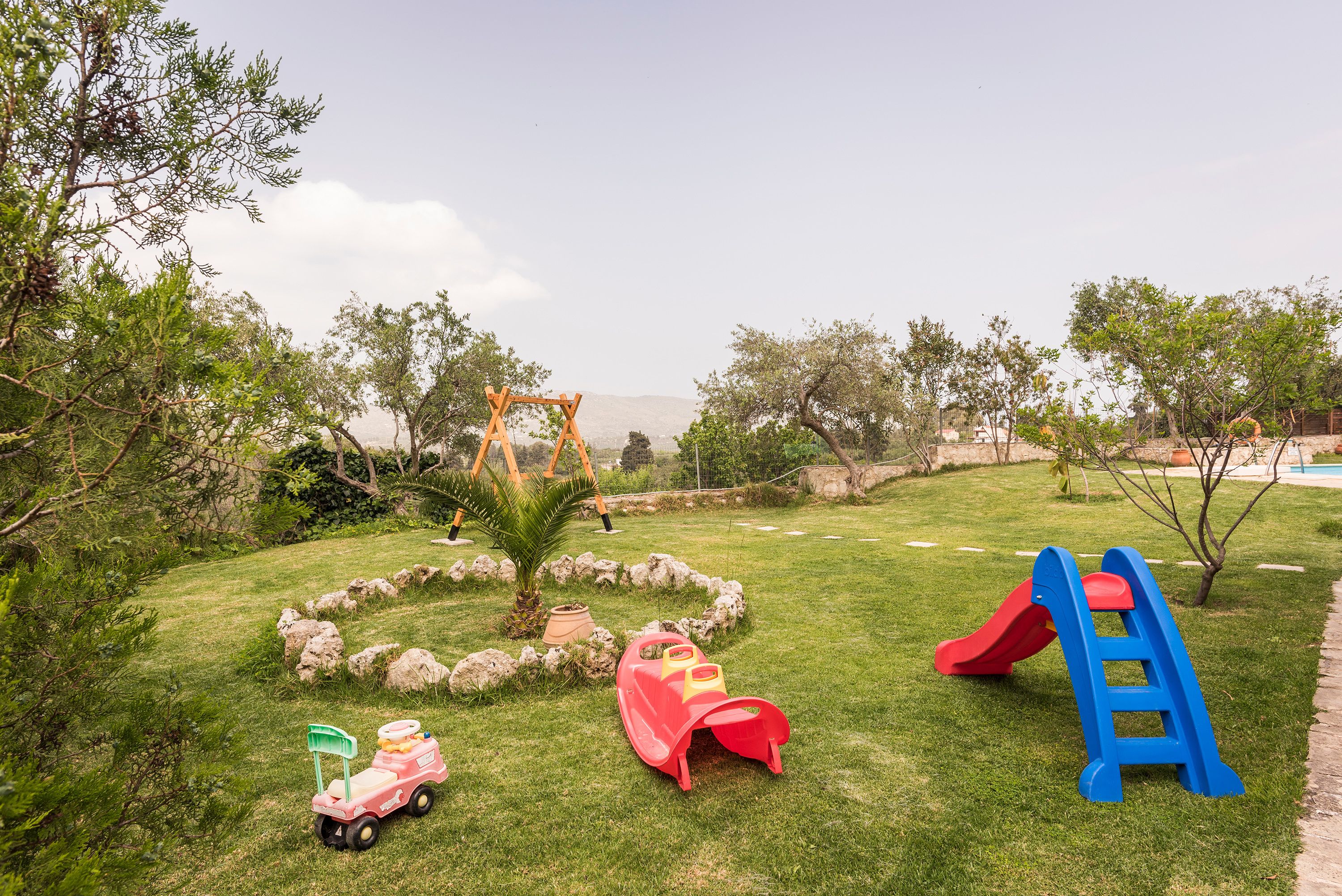 Un parc infantil amb un cadireta, tobogan i un cotxet de joguina.