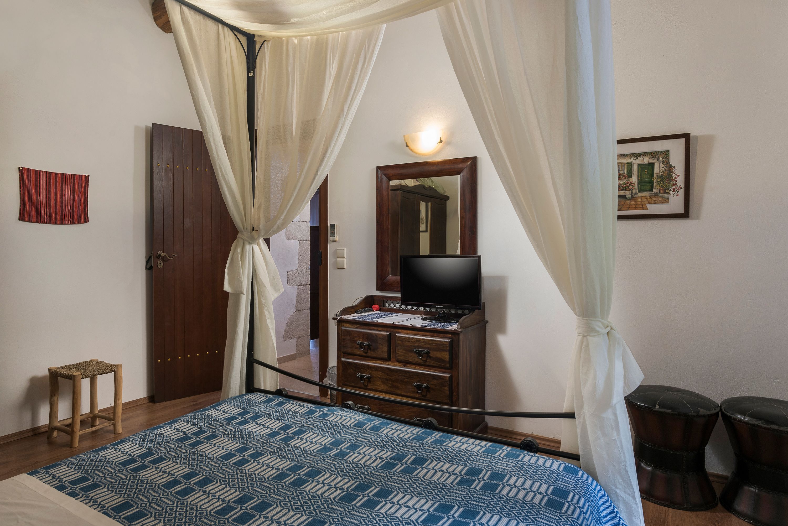 A bedroom with a bed, a dresser, a television, and a curtain.