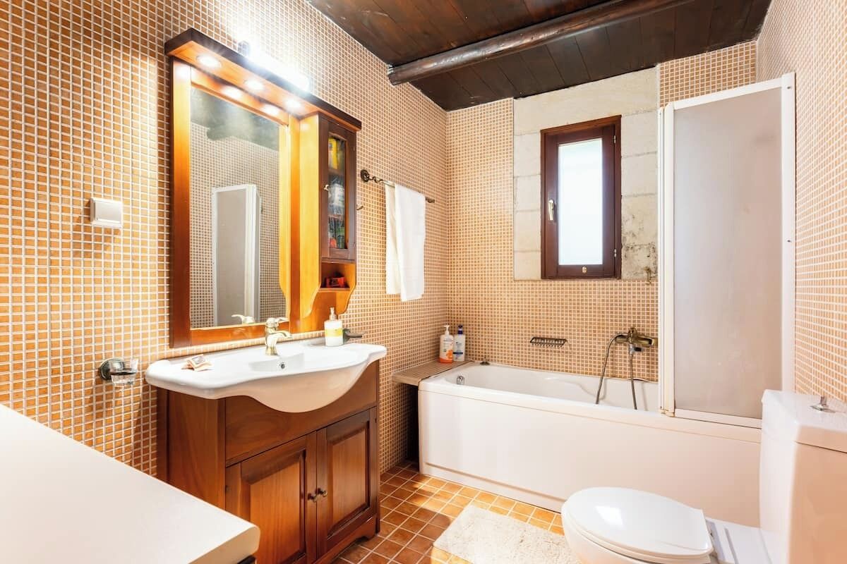 Un baño con tocador de madera, bañera y retrete.