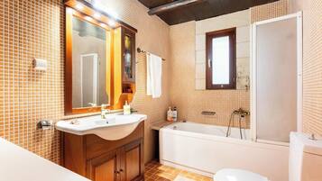 Un baño con tocador de madera, bañera y retrete.