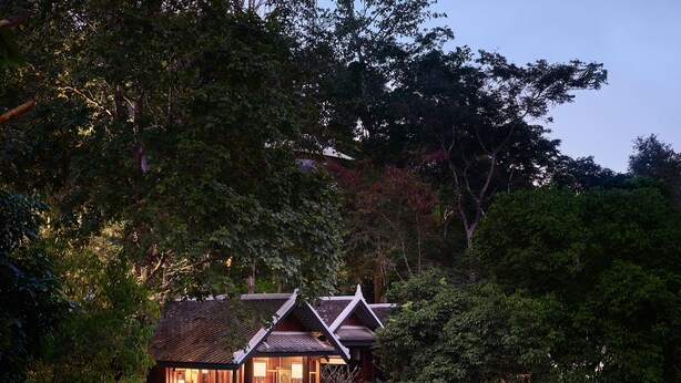 Een afgelegen lodge met een waterval, omgeven door dicht bos.