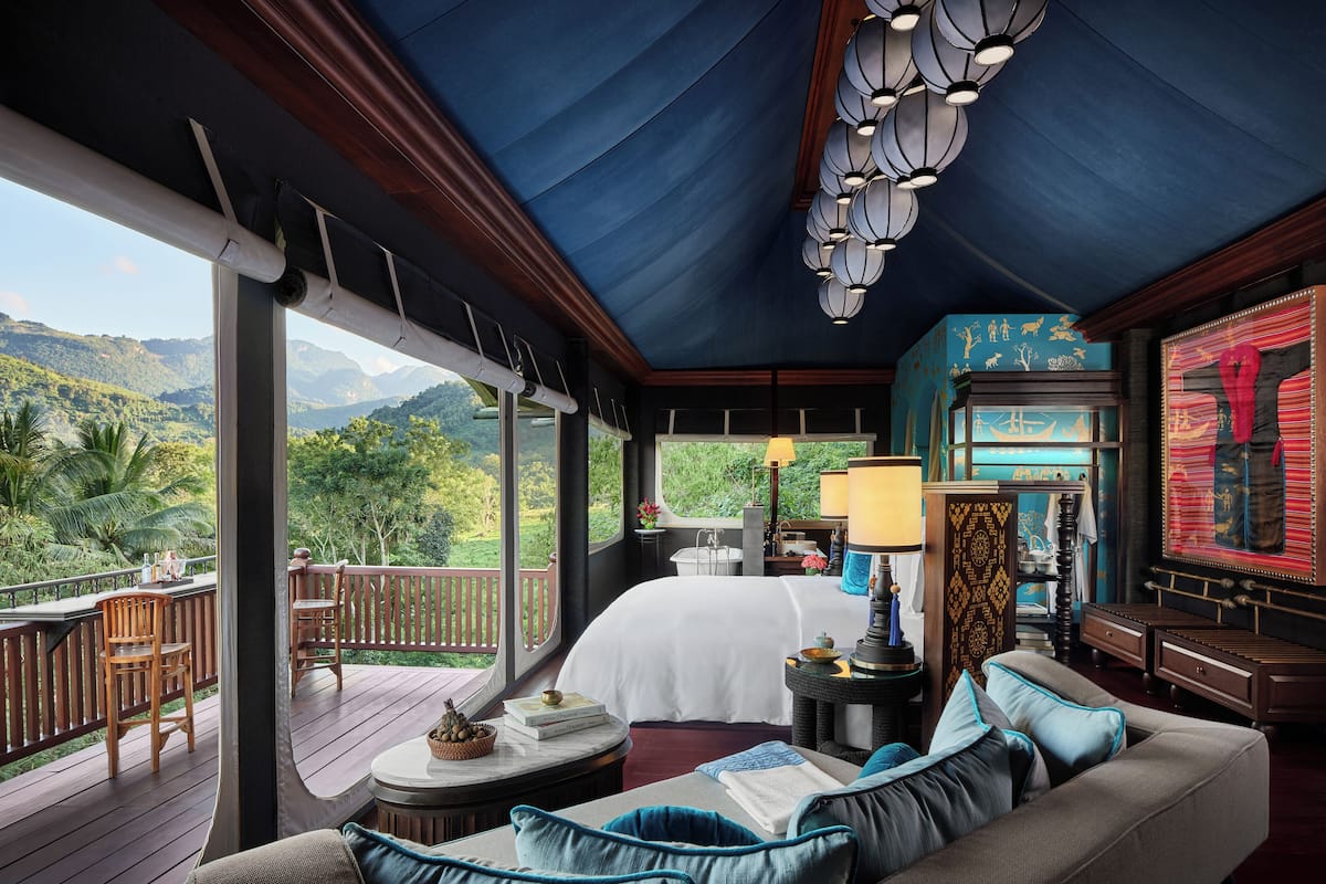 Une chambre avec un grand lit, un balcon doté de meubles en bois et une vue sur les montagnes.