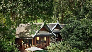 Een houten lodge met een zwembad en een waterval.