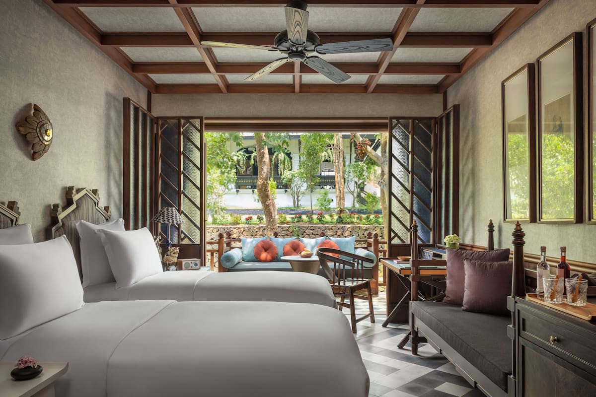 Une chambre d’hôtel avec deux lits, un coin repas et une vue sur l’extérieur.