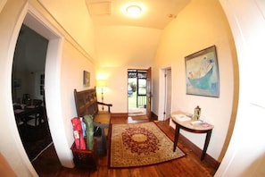 A hallway with a wooden floor, a patterned rug, a table with a vase, and a painting on the wall. - Belfield Beach Estate (Sandys Parish)