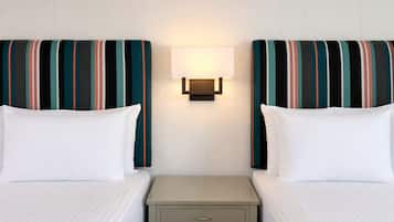 Une chambre d’hôtel avec deux lits, une table de chevet et une lampe fixée au mur.