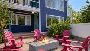 A patio with red Adirondack chairs and a fire pit. - The Foxberry - A Digital Concierge Guesthouse (Provincetown)