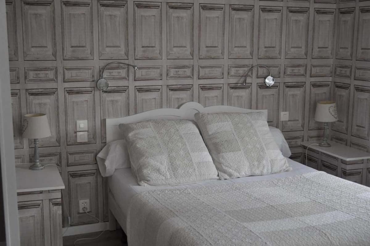 A bedroom with a bed, two bedside tables, and a wall with a panel design.