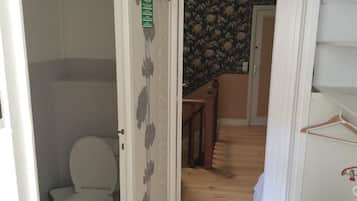 Ein Badezimmer mit Toilette, Duschbereich und Holzboden.
