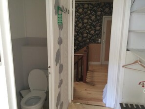 A bathroom with a toilet, a shower area, and a wooden floor. - La Villa Saint Pierre (Epernay)
