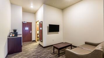 Una hall d'albergo con una reception, un televisore a schermo piatto montato al muro, un divano e un tavolino.