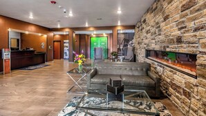 A lobby with a reception desk, a green door, a fireplace, and a leather sofa.