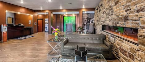 A lobby with a reception desk, a green door, a fireplace, and a leather sofa.