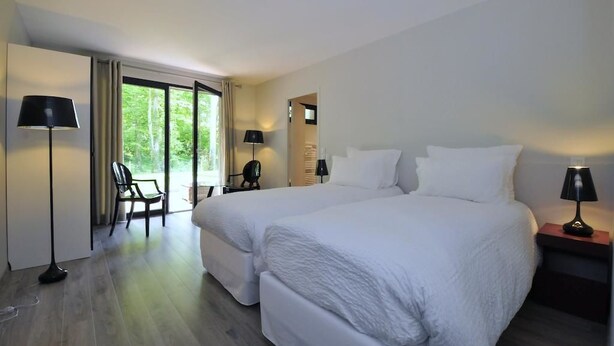 Une chambre d’hôtel avec deux lits, une chaise, un bureau et une lampe.