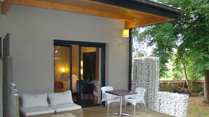 Un espace extérieur abrité, aménagé avec des meubles en osier, une table et des chaises.